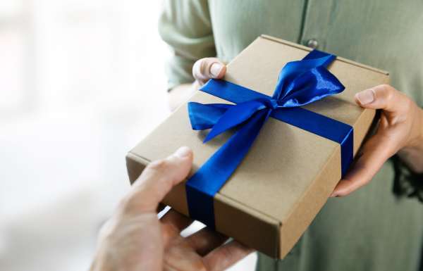 Kunden werben Kunden: Schmidt-Rudersdorf weiterempfehlen Hand überreicht Geschenk mit blauer Schleife an Person mit grünem Hemd