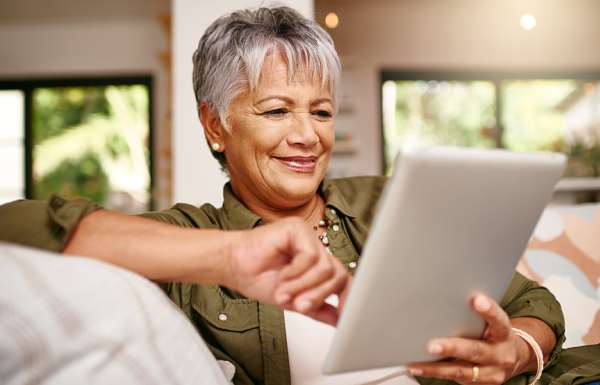 Weiterempfehlung von Kunden Ältere Dame tippt etwas auf einem Tablet und freut sich über Prämie für Weiterempfehlung